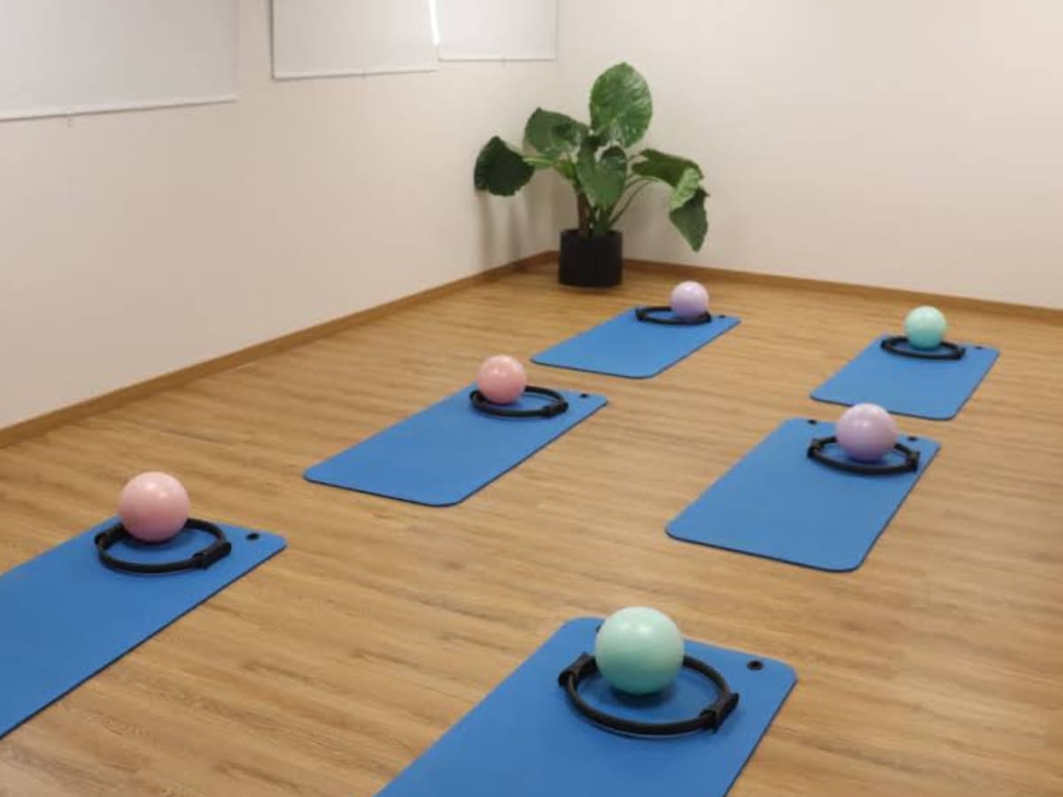 Sala de pilates clínico da AC CLINIC com tapetes, bolas e acessórios de exercício.