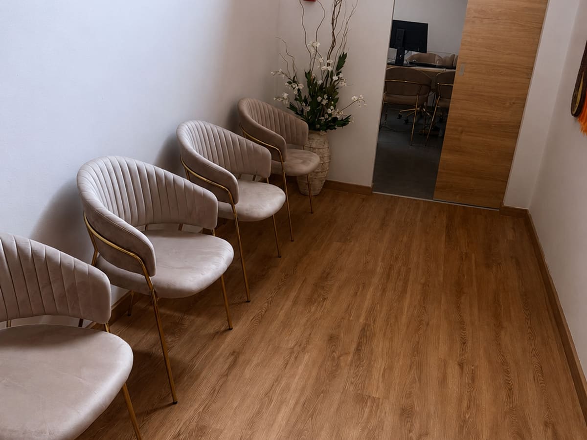 Sala de espera da AC CLINIC com cadeiras estofadas e decoração natural.