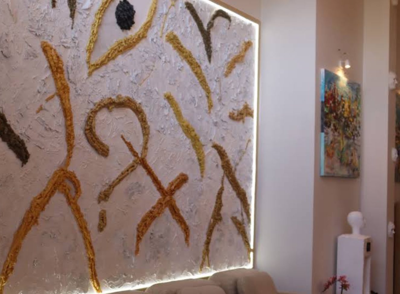 Interior da AC CLINIC, no Porto — sala principal com painel de arte têxtil dourada em relevo, iluminação ambiente quente